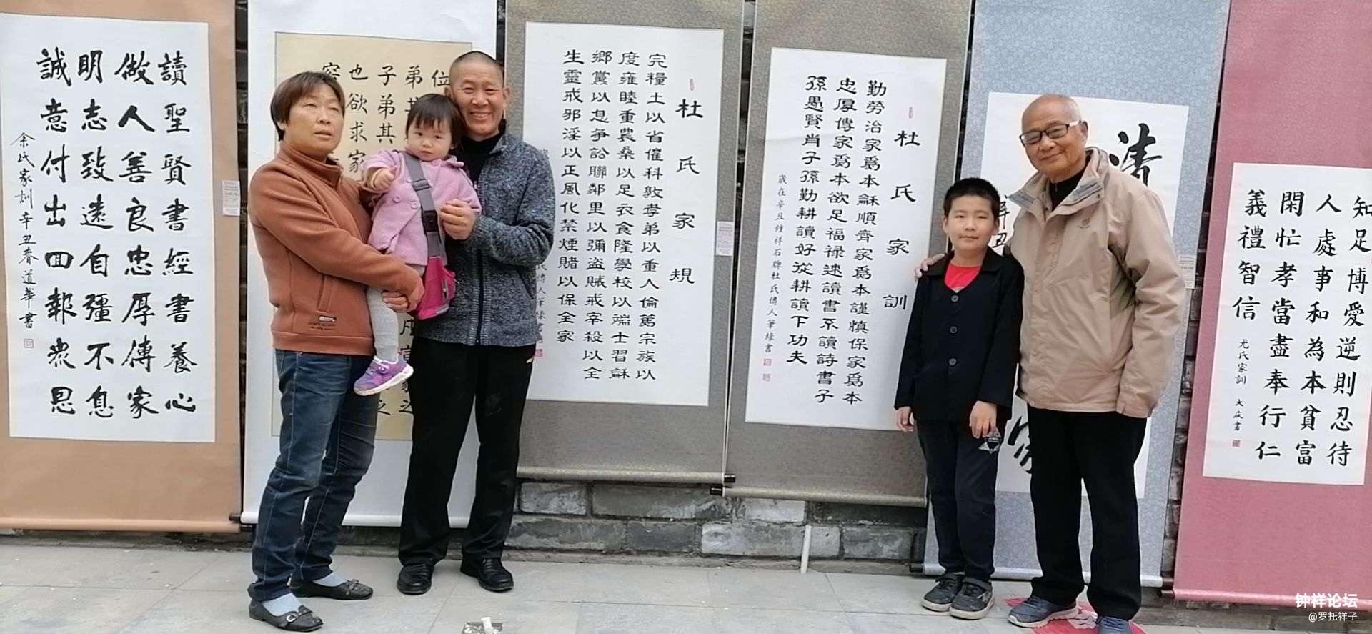 杜晓栋（右一）与二子儿媳和重孙子重孙女在杜氏家训书画作品前合影留念